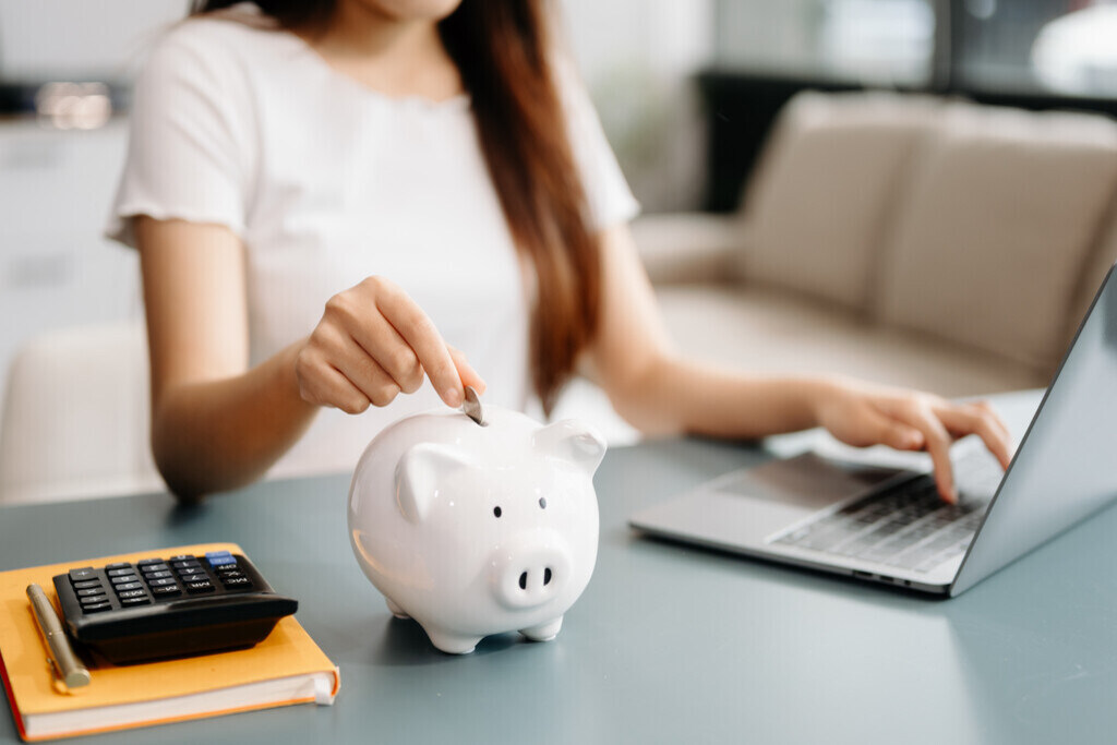 Mulher guardando dinheiro no cofrinho para investir em uma carteira de investimentos moderada