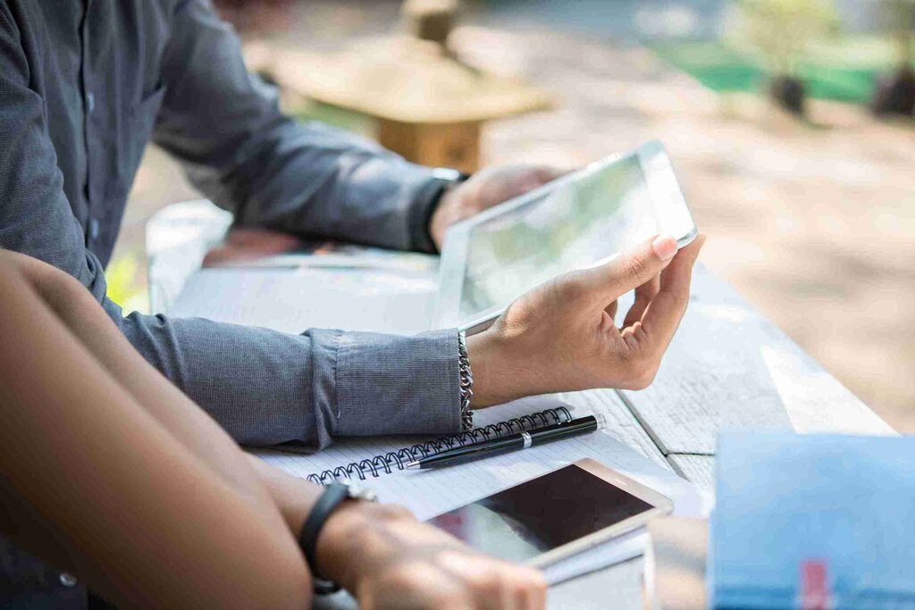 pessoas com papeis, tablet e celular para pesquisar sobre letra de crédito de desenvolvimento