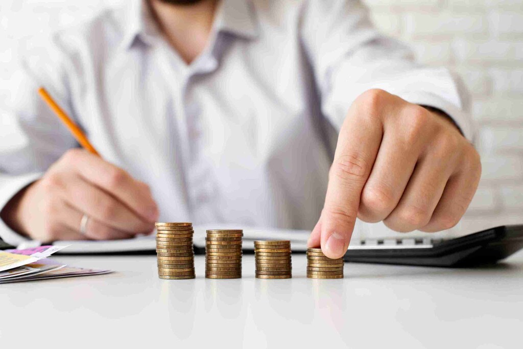 pessoa empilhando moedas em fileiras separadas, representando o rebate