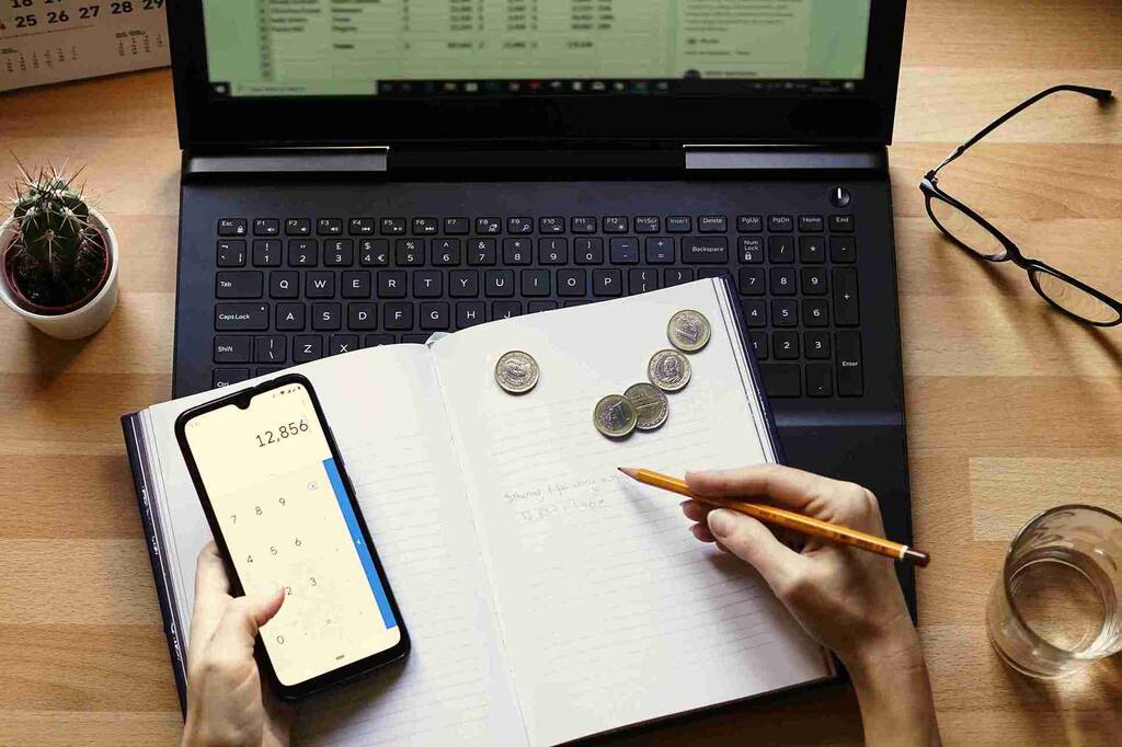 investidor com notebook, celular e caderno para saber como analisar um FII