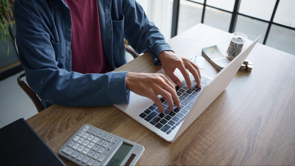Investidor utilizando notebook e calculadora para calcular e analisar o LPA (Lucro por Ação).