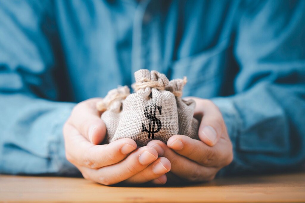 Investidor segura sacos de dinheiro representando o recebimento de proventos em BDRs.