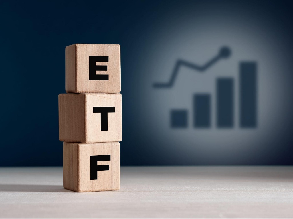 Cubos com as letras ETF empilhados e gráfico de crescimento ao fundo, representando os ETFs que pagam dividendos