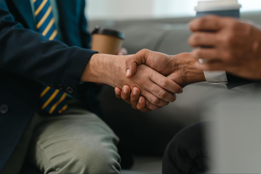 Investidores se cumprimentando com as mãos, representando as negociações no mercado secundário