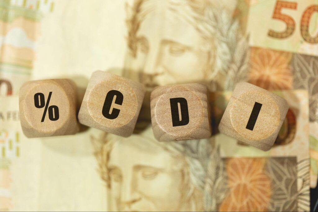 Peças de madeira formando a palavra %CDI sobre notas de R$ 50.