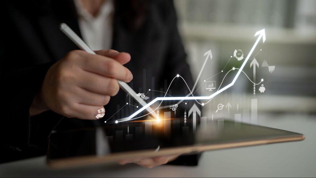 Detalhe de mão de pessoa segurando caneta e tablet, e ícones digitais saindo da tela e representando o payout.