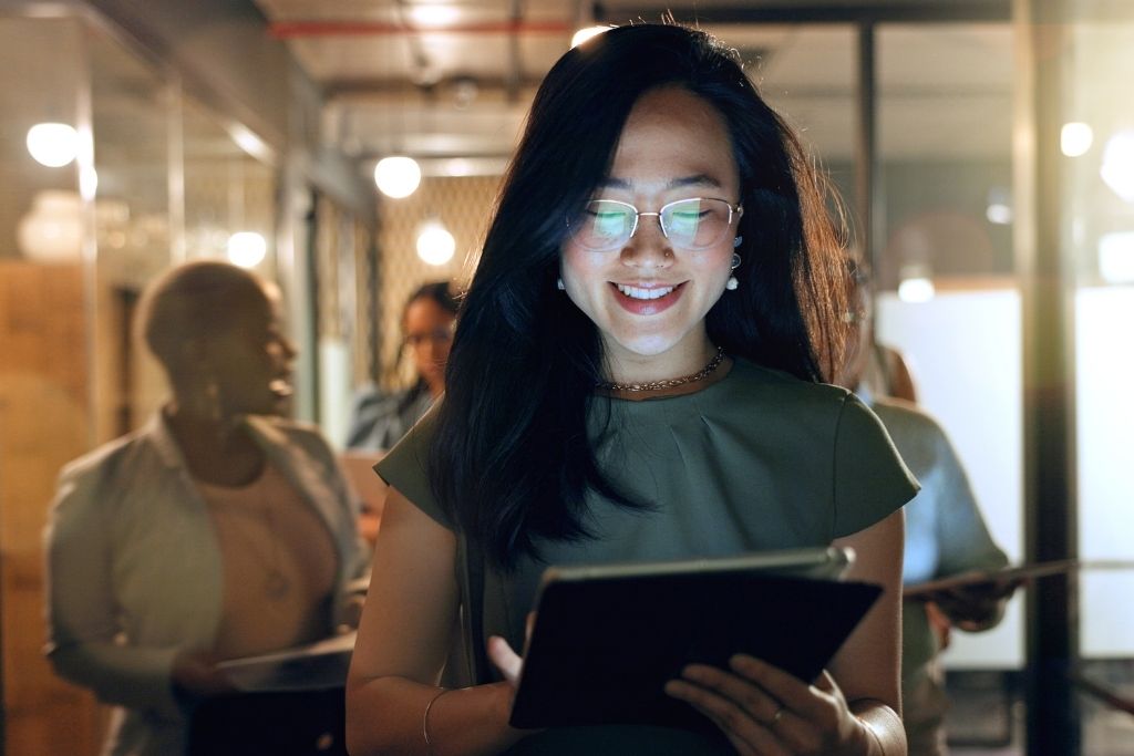 Mulher sorridente em empresa, pesquisando como se tornar investidor profissional.