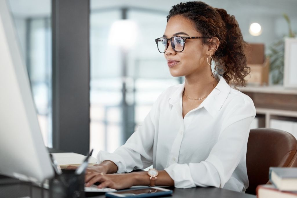 Mulher elegante em ambiente corporativo, utilizando computador para pesquisar por que lca tem imposto de renda.