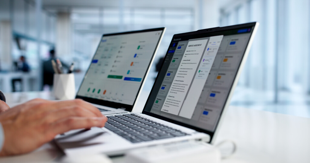 Detalhe de mãos de pessoa utilizando dois computadores para fazer swap.