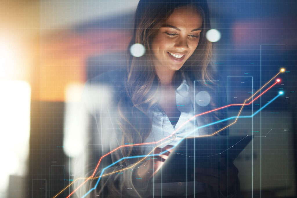 Mulher analisando investimentos no celular com gráficos de alta e queda, representando a volatilidade do mercado.