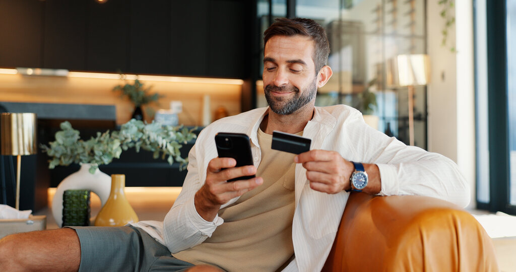 Homem sorridente pesquisando as principais diferenças entre bancos digitais e físicos.