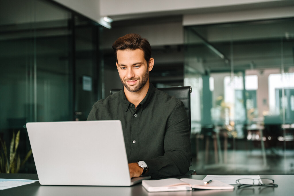 Homem em escritório, pesquisando erros comuns de quem está começando a investir.