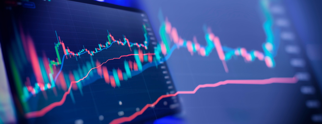 Tela de monitor exibindo um gráfico de velas (candlestick) em tons de verde e vermelho com linhas de tendência, ilustrando indicadores da análise fundamentalista no mercado financeiro.